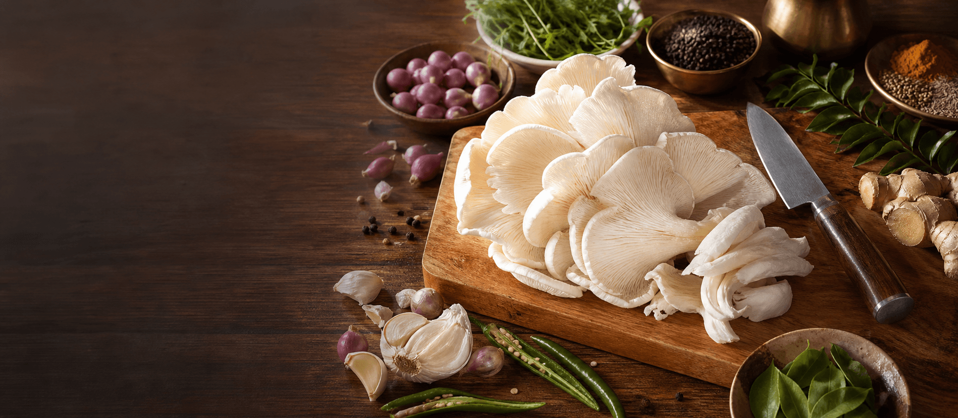 Fresh oyster mushrooms with Kerala cooking ingredients on a wooden cutting board